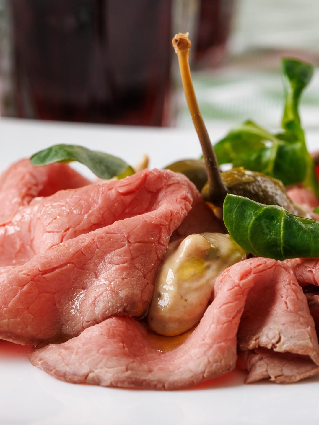 Vitello tonnato: fettine di carne rosata con capperi e foglioline di insalata.